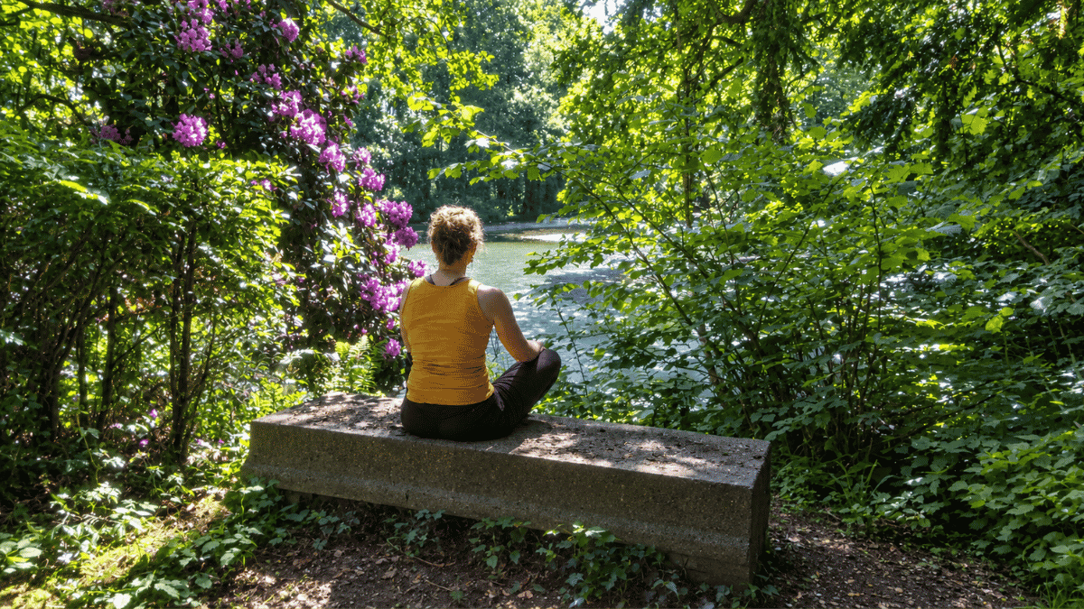 Vrouw zit in stilte op de steen tussen de bomen bij De Refter